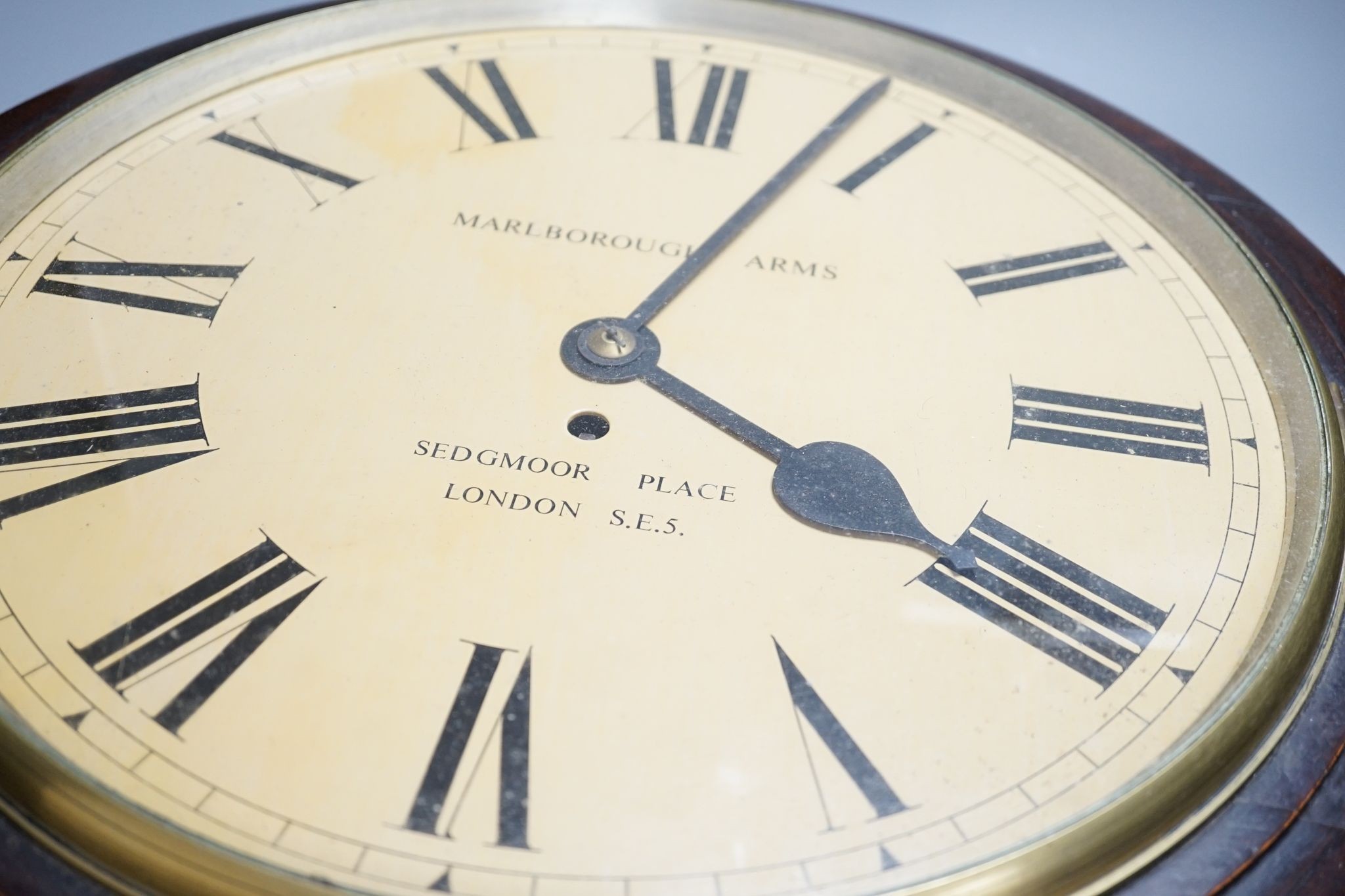 A mahogany dial clock, Marlborough Arms, Sedgmoor Place, London SE5., 48 cms diameter.